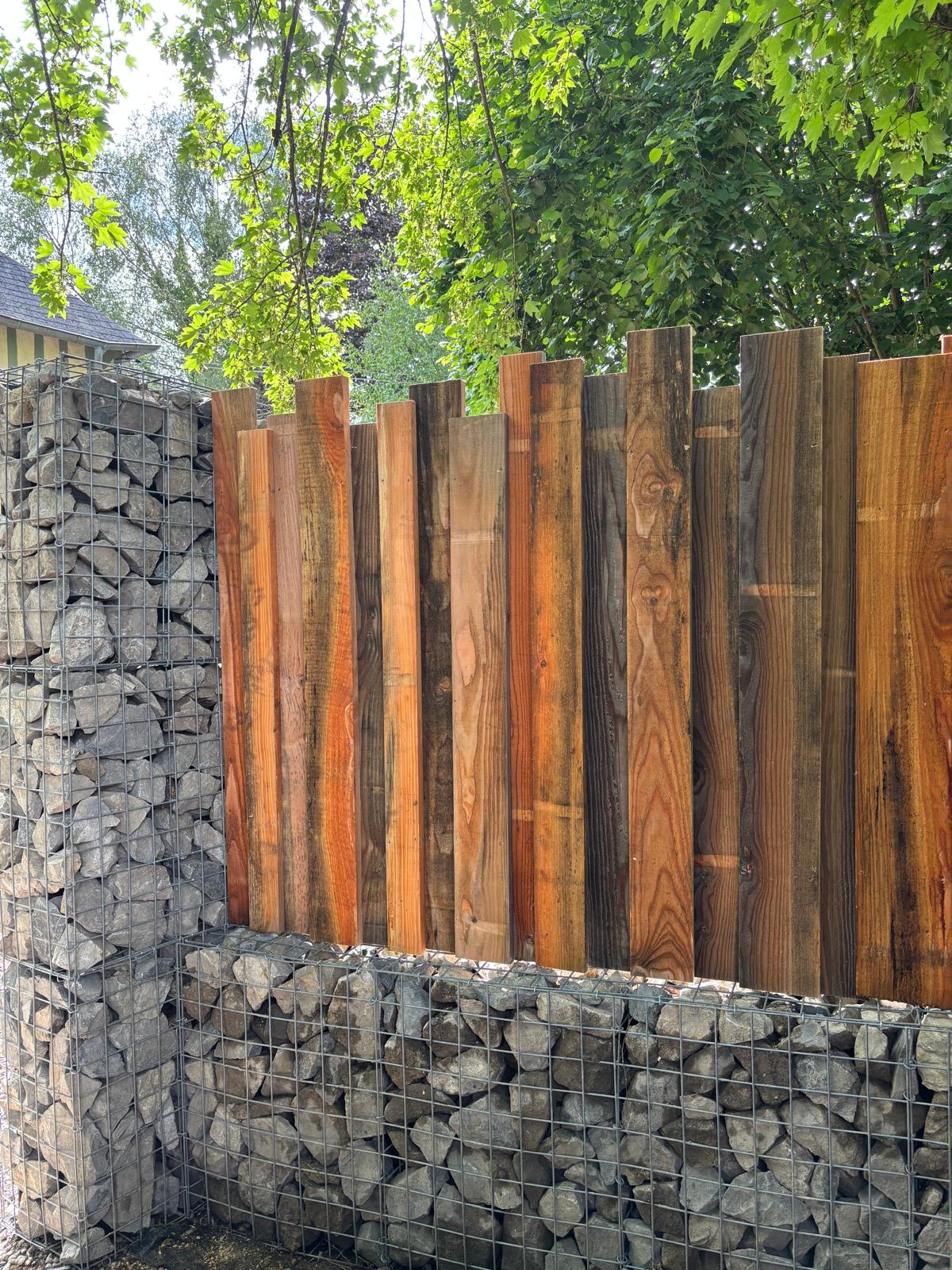 Clôture en lames de bois brut sur muret gabion
