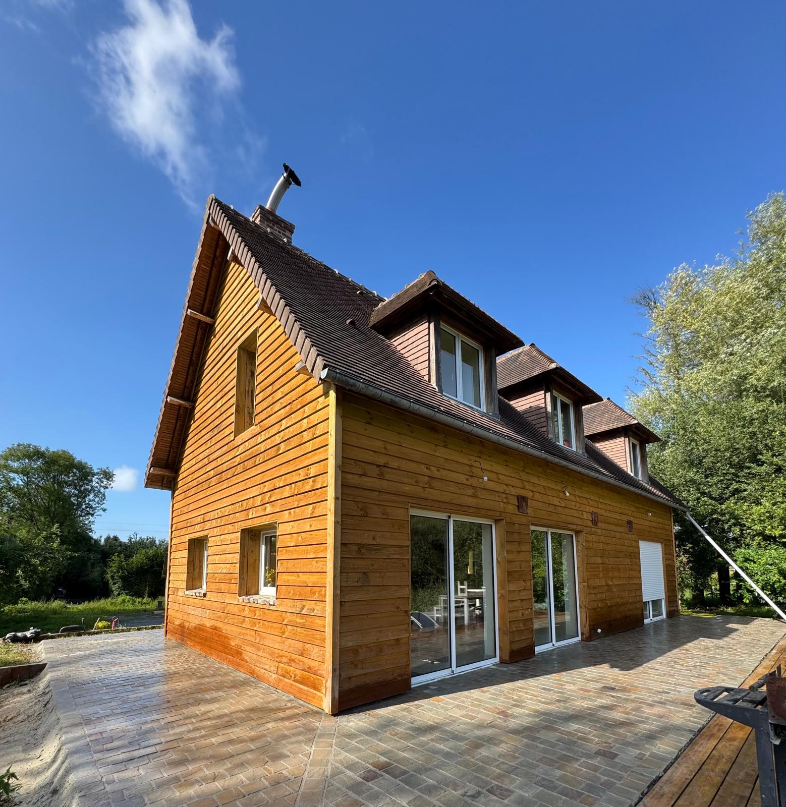 Bardage bois sur maison normande avec terrasse pavée