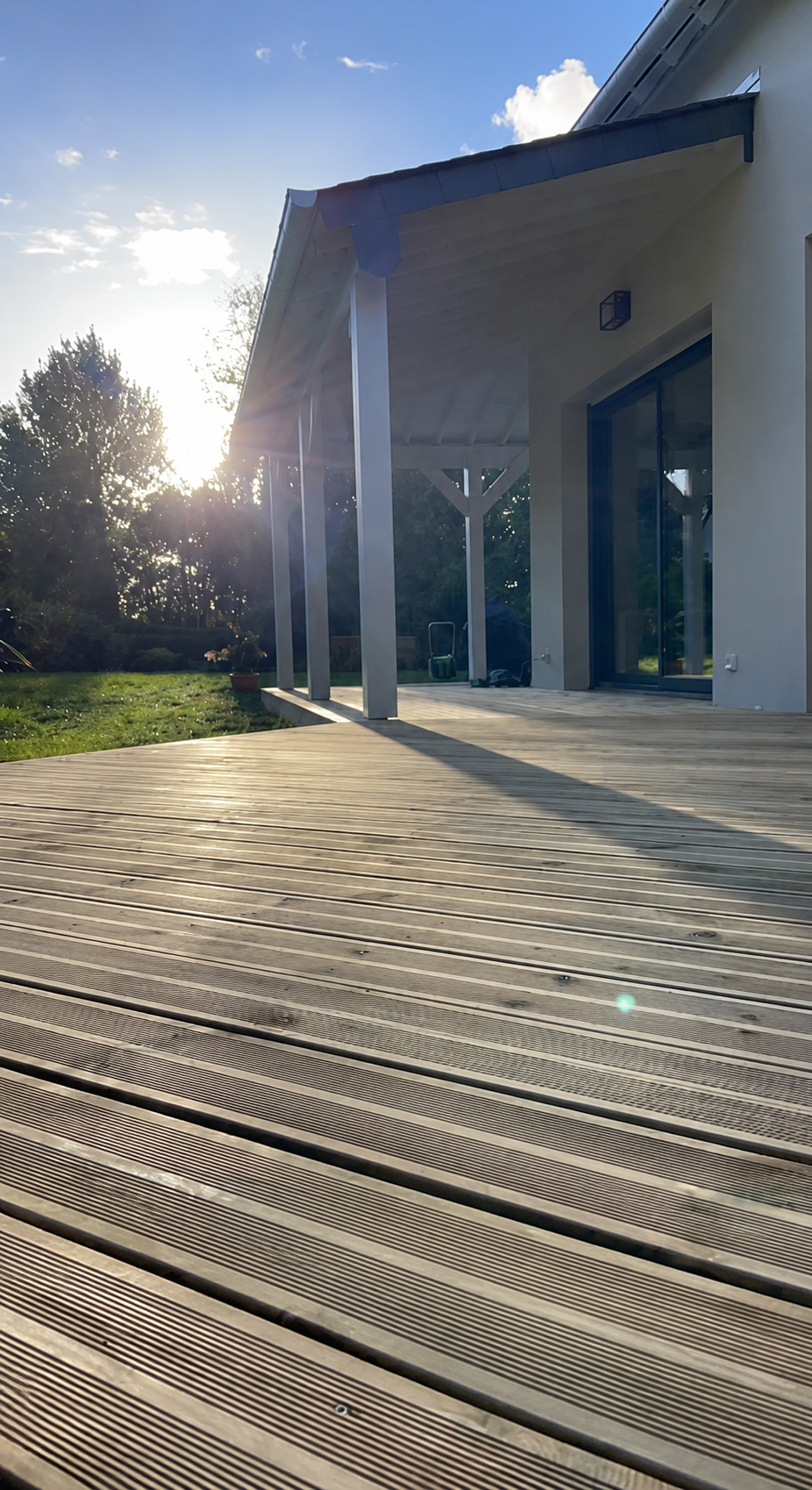 Terrasse bois sous un préau blanc au coucher du soleil